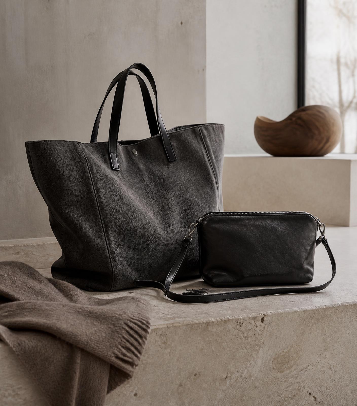 A canvas tote and a small crossbody bag on a pale stone surface in soft winter light