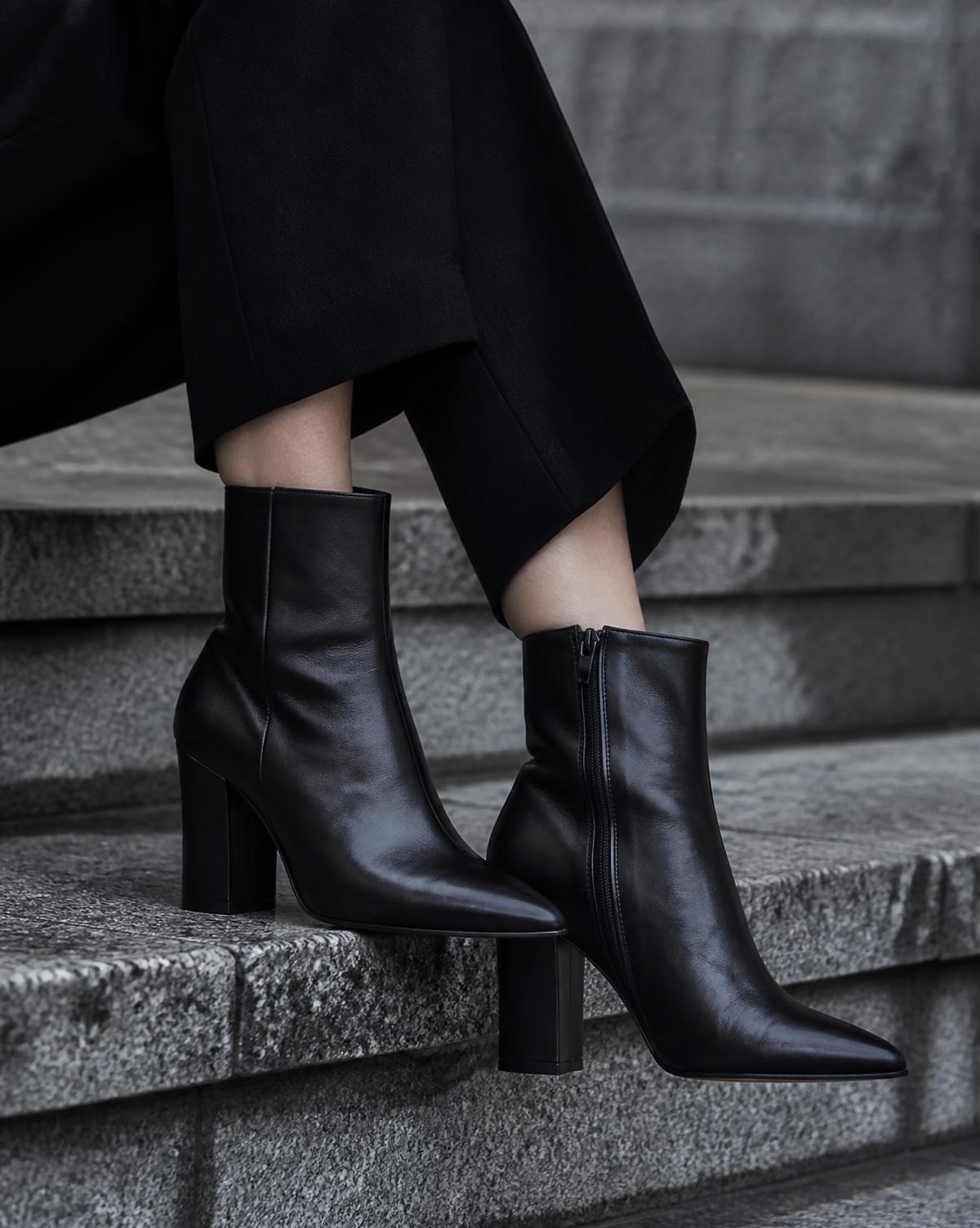 Women's black leather ankle boots with a block heel on cold grey stone steps