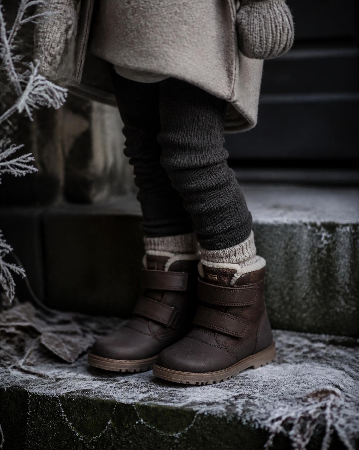 Children's brown winter boots on frosty stone steps